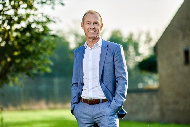 Billede af Jørgen Christensen, administrerende direktør i GK Danmark, taget udendørs med en bygning og et træ i baggrunden.
