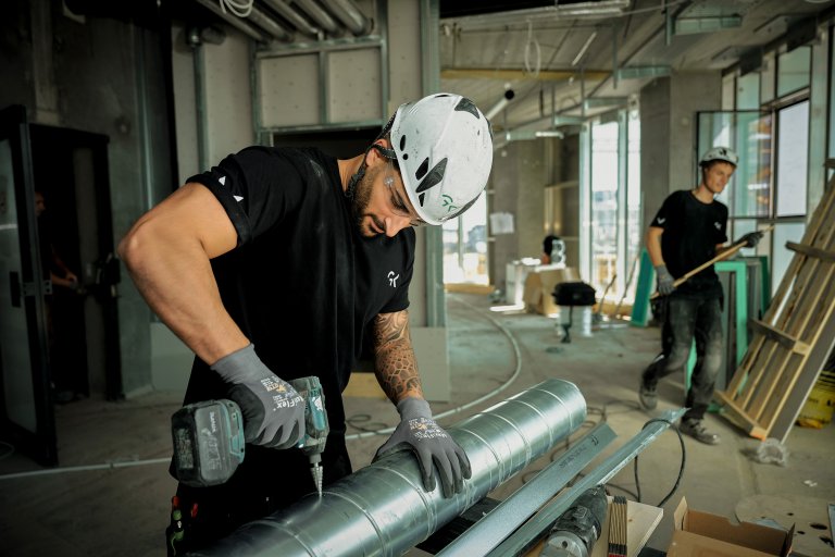 Billede af medarbejder, der borer i ventilationskanal